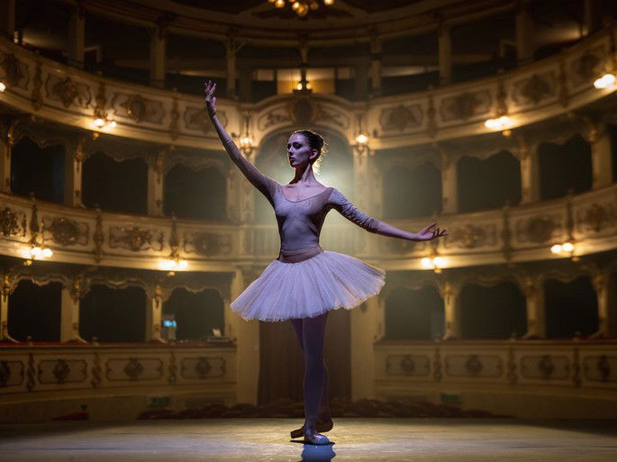 Bailarina de sapatilhas de ponta e tutu branco dançando balé.