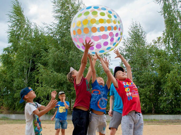 Crianças brincando com uma bola inflável gigante - Jogo de integração de equipe.