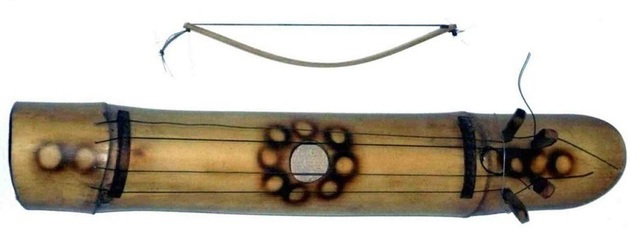 Instrumento tubular com v&aacute;rias cordas, abertura redonda no centro e um arco curvo acima.