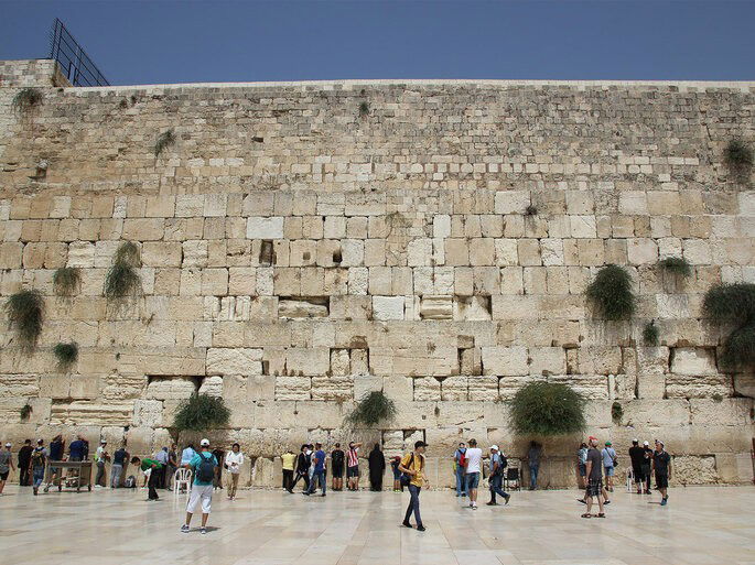 Muro das Lamentações, em Jerusalém. É possível ver o muro, local sagrado para Judeus, além de pessoas em seu entorno. 