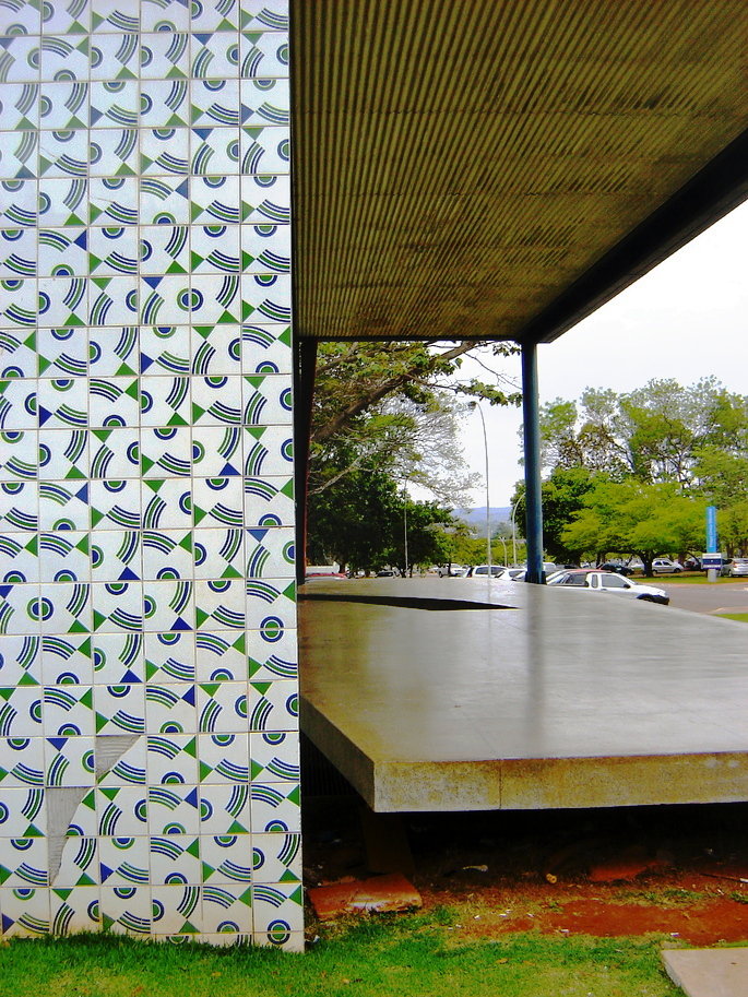 Parede coberta por azulejos brancos com formas geom&eacute;tricas azuis e verdes, organizadas em diferentes posi&ccedil;&otilde;es.