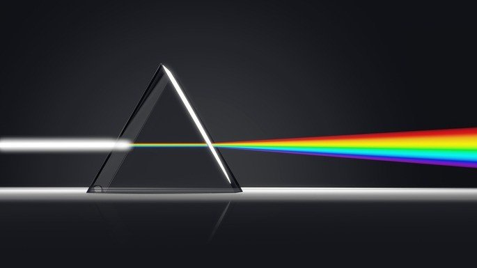 Luz branca sendo refratada por um prisma, separando suas frequências como em um arco-íris.