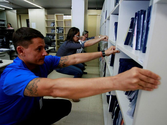 Trabalhadores no escritório segurando estante e realizando alongamentos