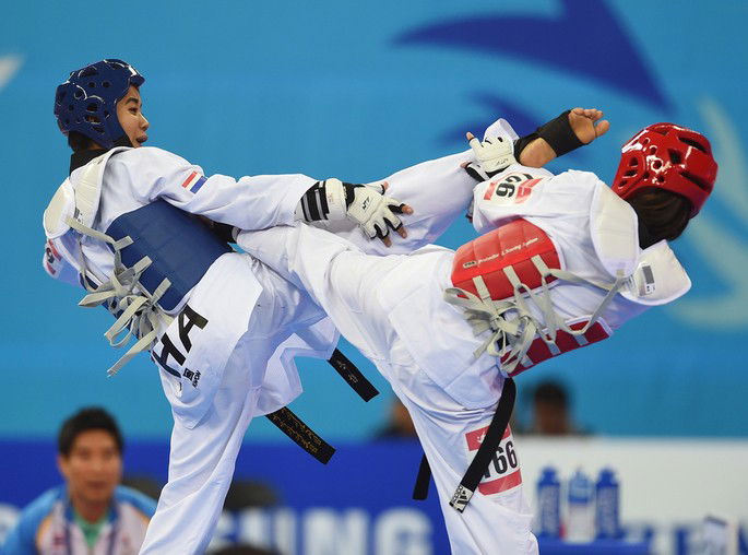 Dois atletas faixas preta lutando Taekwondo em competição