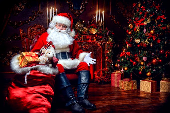 Papai Noel sentado junto à árvore de Natal e à lareira
