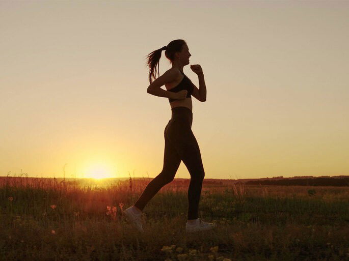 Mulher correndo ao pôr do sol.
